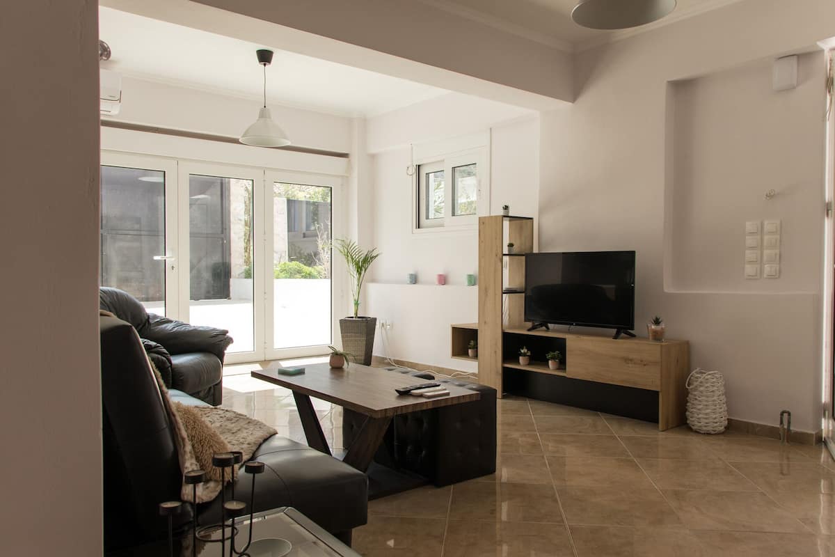 A modern living room with a sofa, coffee table, TV, and a dining area.