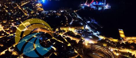 Une vue aérienne d’une ville de nuit, avec des rues illuminées et un grand stade.