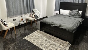 Un dormitorio moderno con una cama grande, una silla, una mesita y una alfombra.