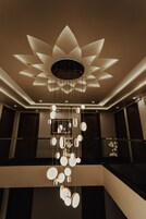 A modern interior with a unique ceiling design, a hanging light fixture, and a staircase.
