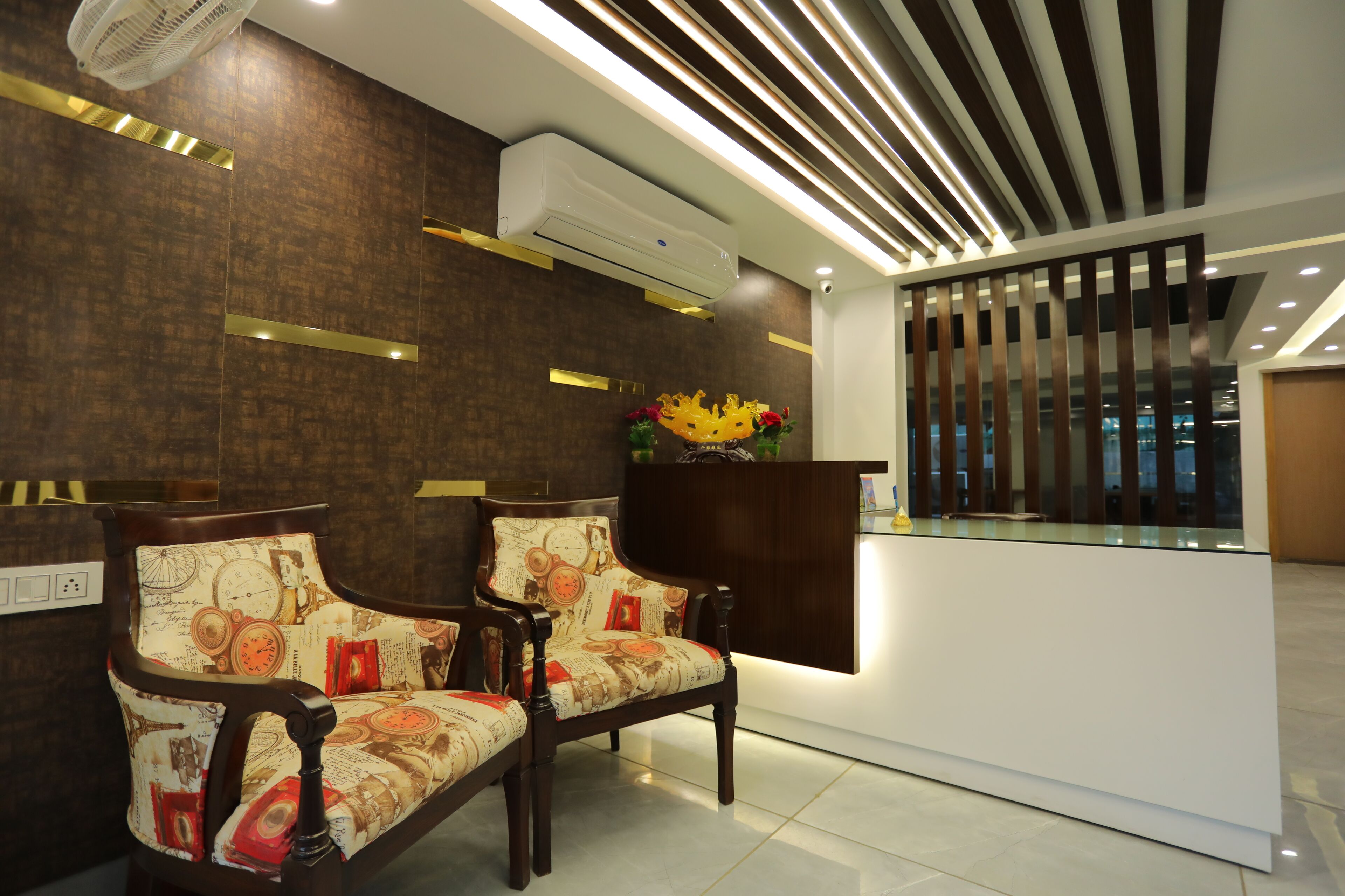 A reception area with two upholstered chairs, a reception desk, and a modern ceiling design.