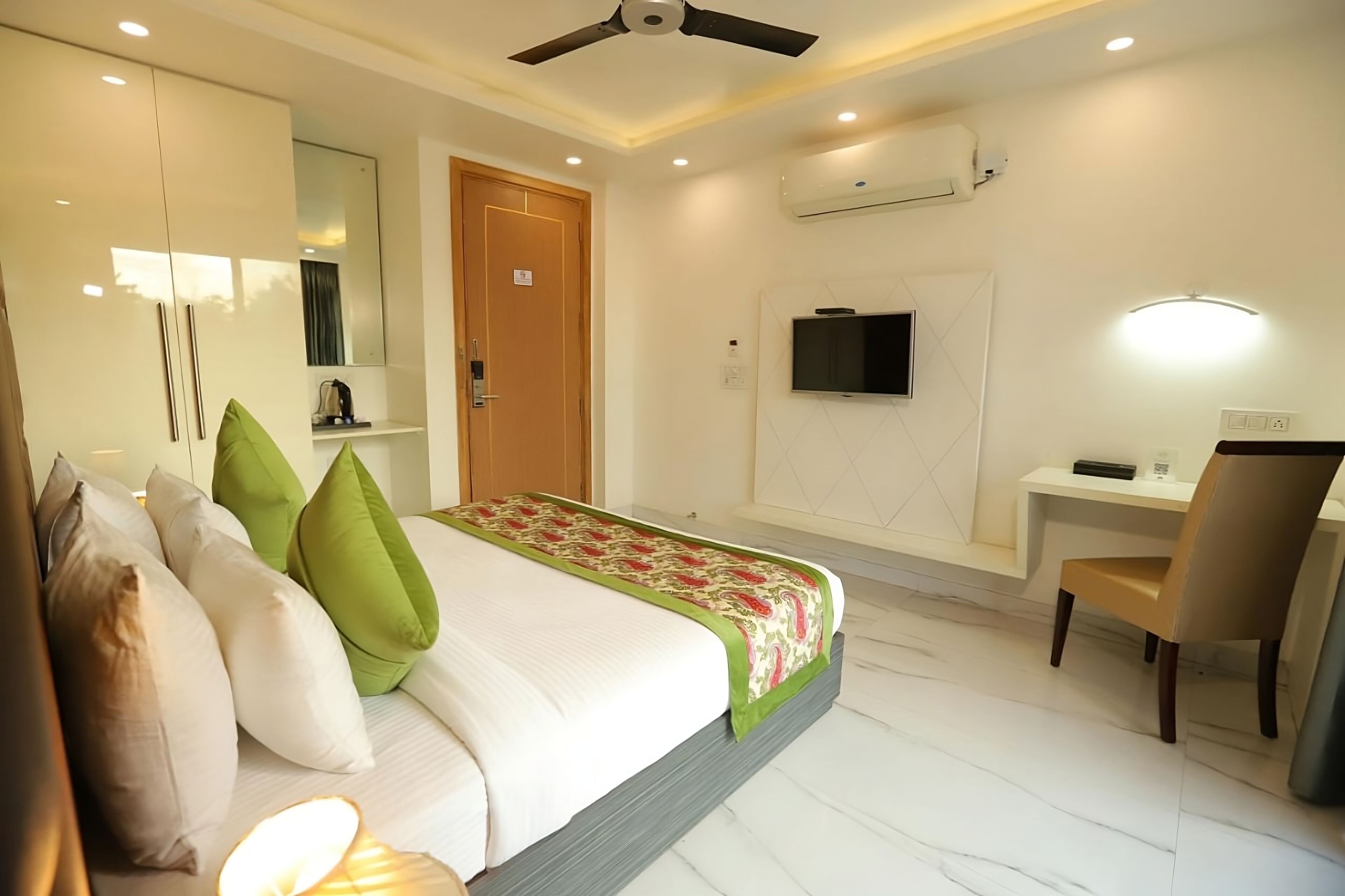A hotel room with a bed, a desk, a chair, a ceiling fan, and an air conditioning unit.