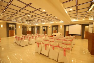 A spacious hall with rows of chairs, a projector screen, and a polished floor.