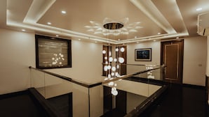 A modern interior with a glass railing, a decorative light fixture, and a framed artwork on the wall. - Hotel Keshav Residency - Medicity Gurugram, near Medanta Hospital (Gurugram)