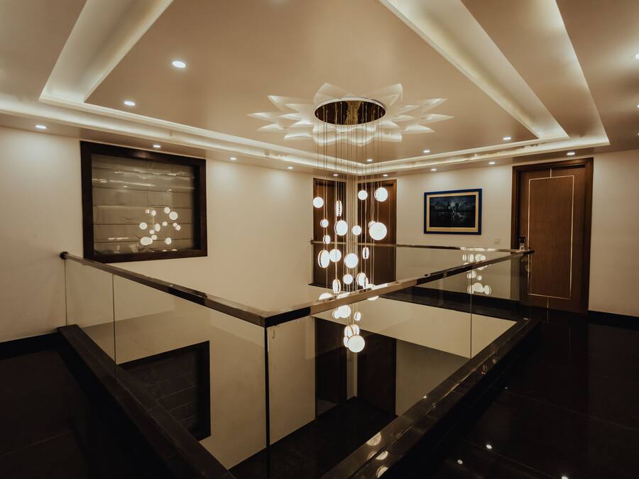 Een modern interieur met een glazen balustrade, een decoratieve lamp en een ingelijste kunstwerk aan de muur.