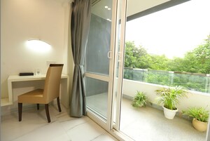 A room with a desk, chair, and a sliding glass door leading to a balcony with potted plants.