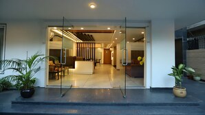 A modern hotel entrance with a reception desk, glass doors, and potted plants. - Hotel Keshav Residency - Medicity Gurugram, near Medanta Hospital (Gurugram)