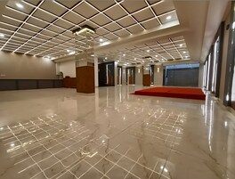 Un lobby espacioso con piso de mármol pulido, alfombra roja y un diseño de techo moderno con iluminación empotrada.