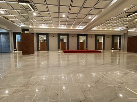 A spacious lobby with a polished marble floor, a red carpet, and a modern ceiling design.