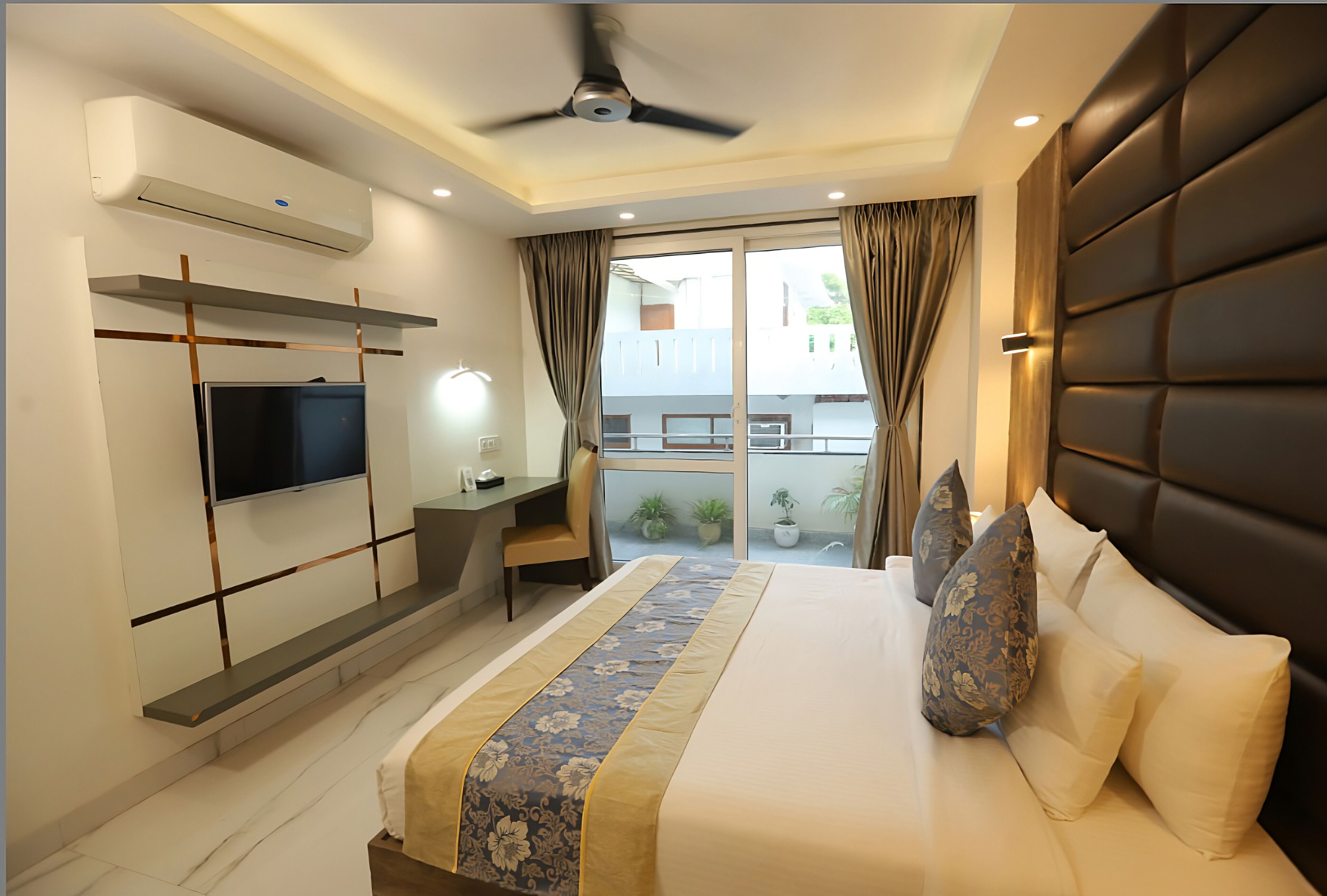 Ein modernes Hotelzimmer mit Bett, Schreibtisch, Fernseher und einem Balkon mit Vorhängen.