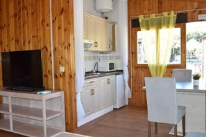 A compact kitchen with wooden walls, a white countertop, a microwave, and a sink.