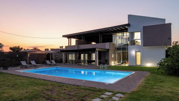 Et moderne hus med to etager, en swimmingpool, udendørs siddepladser og en overdækket terrasse.