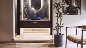 Un baño moderno con un espejo grande, un lavabo azul y una planta en maceta.