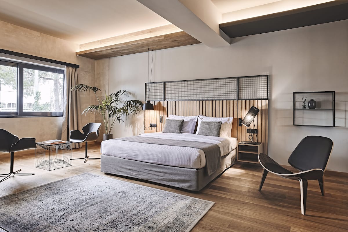 A modern bedroom with a large bed, a wooden ceiling, a view of the outdoors, and a minimalist decor.