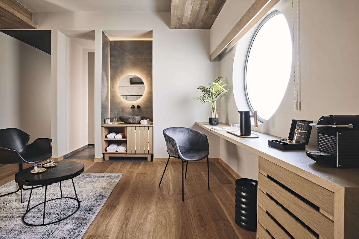 A modern bathroom with a wooden vanity, a large mirror, and a potted plant.