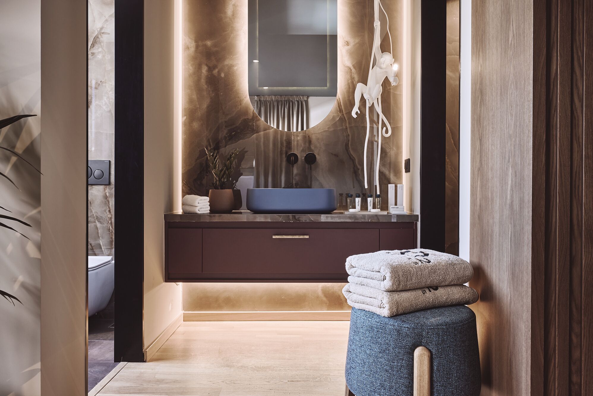 Un baño moderno con tocador de mármol, un lavamanos azul y una pila de toallas.