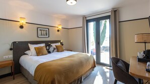 A hotel room with a large bed, a desk, and a view of the outdoors. - Les Villas du Château de Lastours (Portel-des-Corbières)