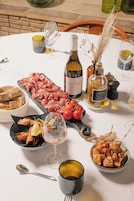 Una mesa dispuesta con diversos alimentos, botellas de vino y copas, que sugiere una experiencia gastronómica.