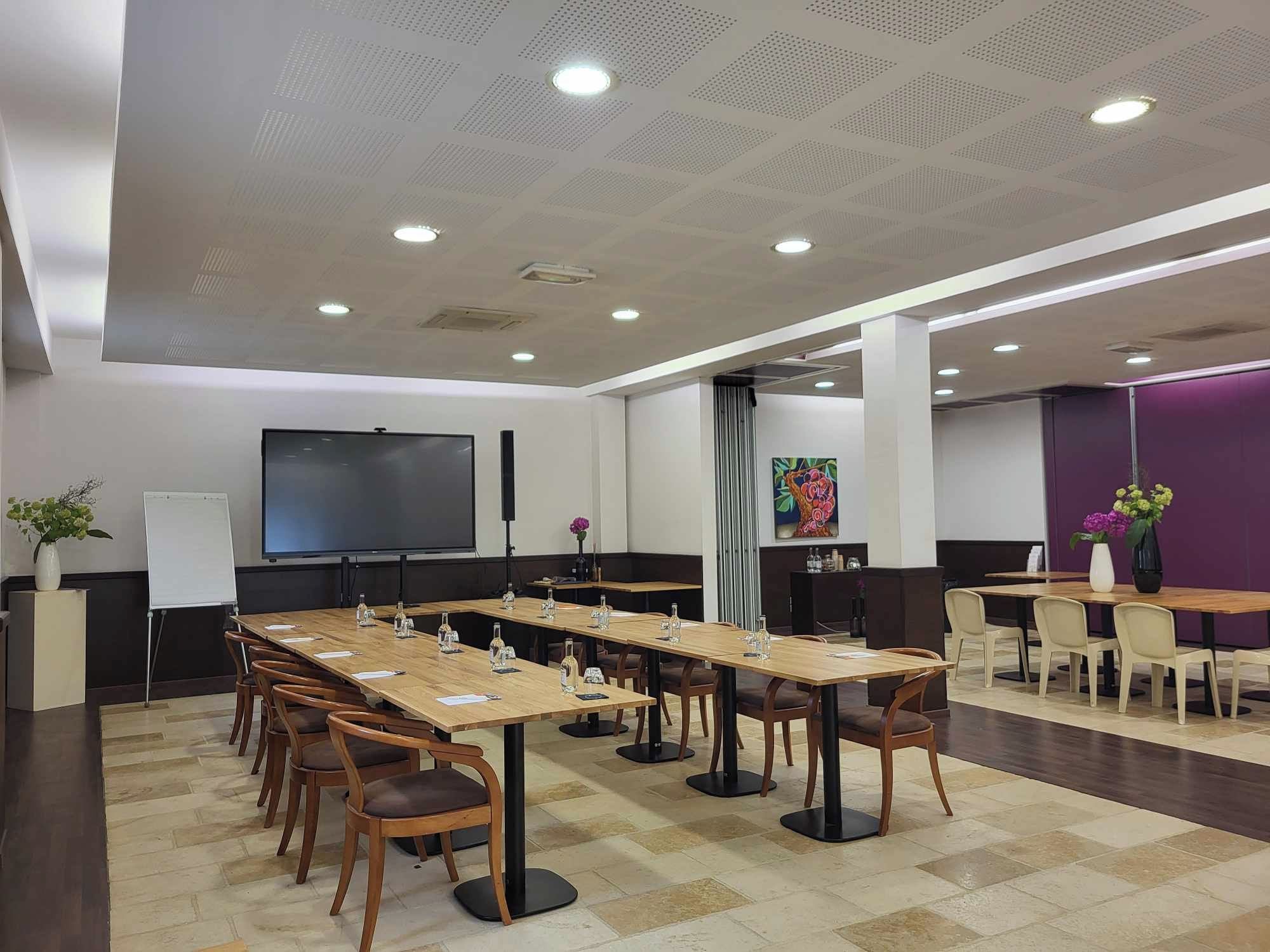 A conference room with a long table, chairs, a projector screen, and a whiteboard.