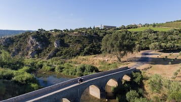 A stone bridge over a river with a motorcycle on it, surrounded by greenery and hills.