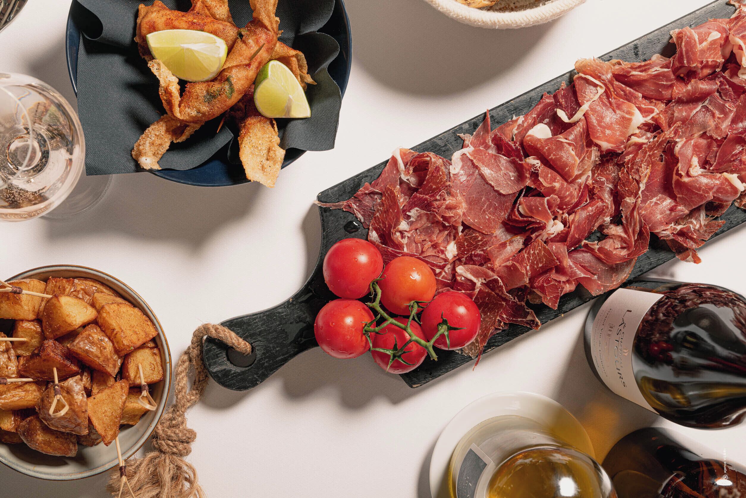 Diversos alimentos, incluyendo opciones fritas, una tabla de embutidos y un bol de patatas asadas.