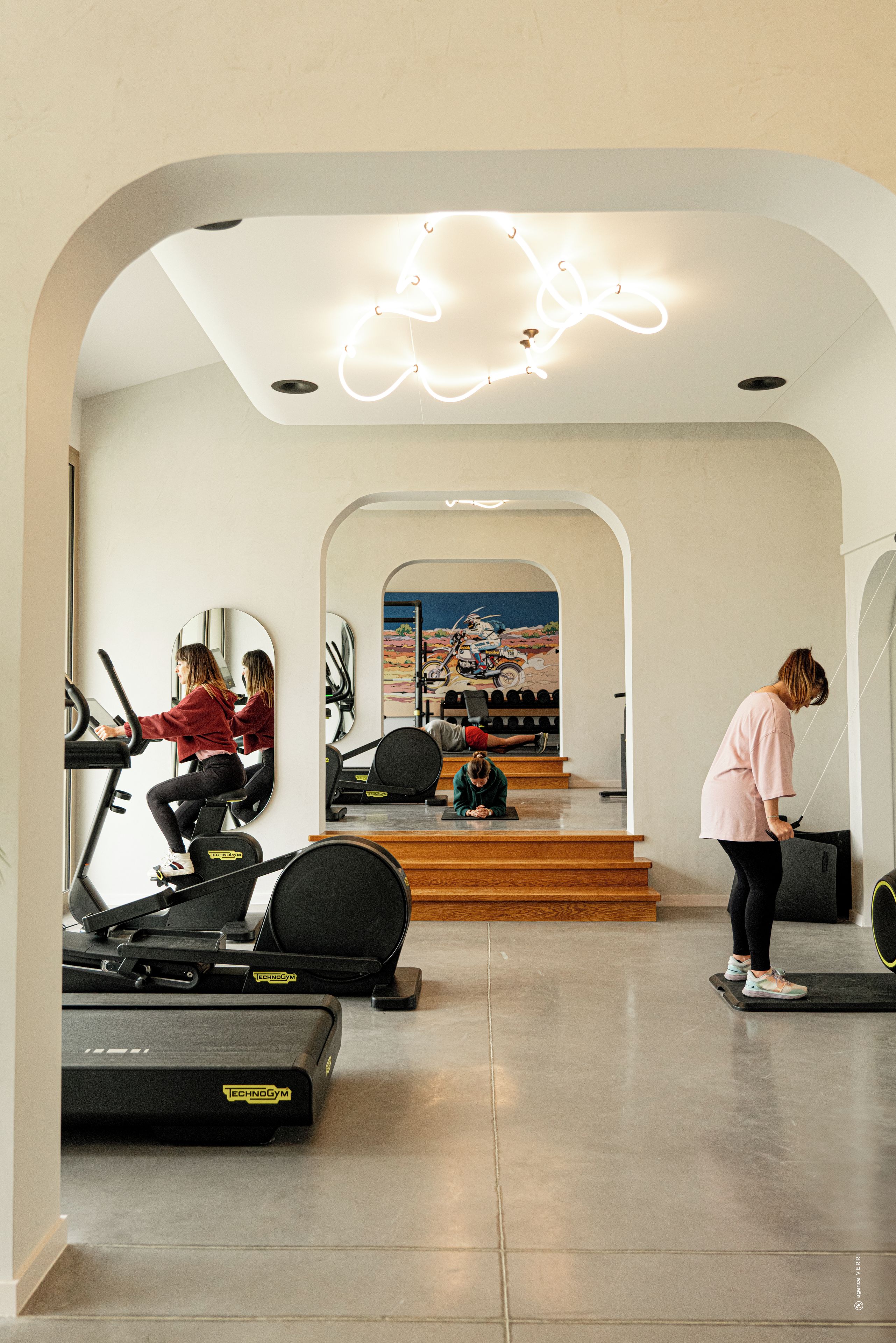 Un gimnasio con equipo de ejercicio, un espejo y un mural en la pared.