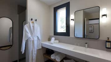 Un baño moderno con un tocador blanco, un espejo grande y una bata colgada en un perchero.