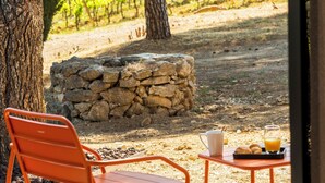 A patio with a table and a chair, a stone wall, and a vineyard view. - Les Villas du Château de Lastours (Portel-des-Corbières)