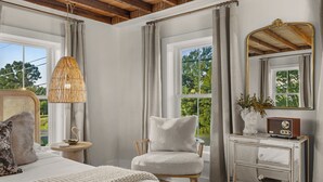 A bedroom with a bed, a chair, a dresser, a mirror, and a lamp.