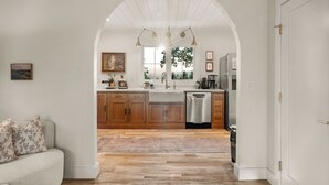A modern kitchen with wooden cabinets, a dishwasher, and a large window.