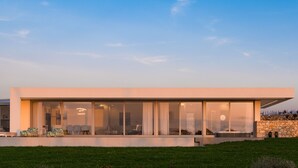 Una casa moderna con amplios ventanales, techo plano y pared de piedra.