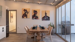 Un comedor moderno con una mesa de madera, seis sillas y tres obras de arte en la pared.