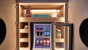 Un refrigerador compacto con varios estantes, que contiene diversas bebidas y condimentos.