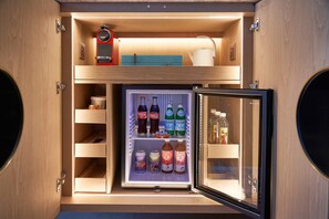 Een compacte koelkast met verschillende planken, gevuld met diverse dranken en sauzen.