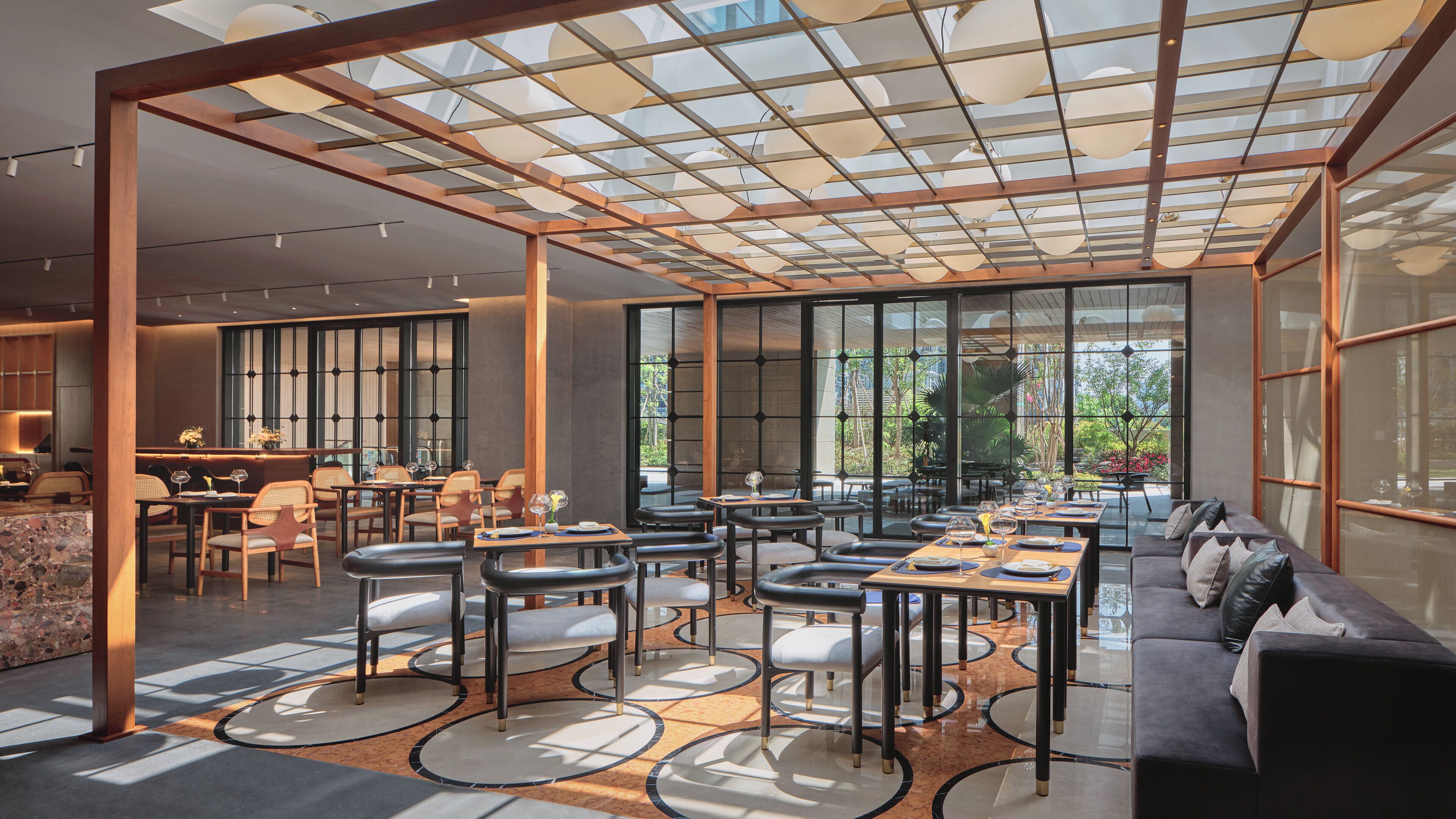 A modern interior with a dining area, seating arrangements, and large windows.