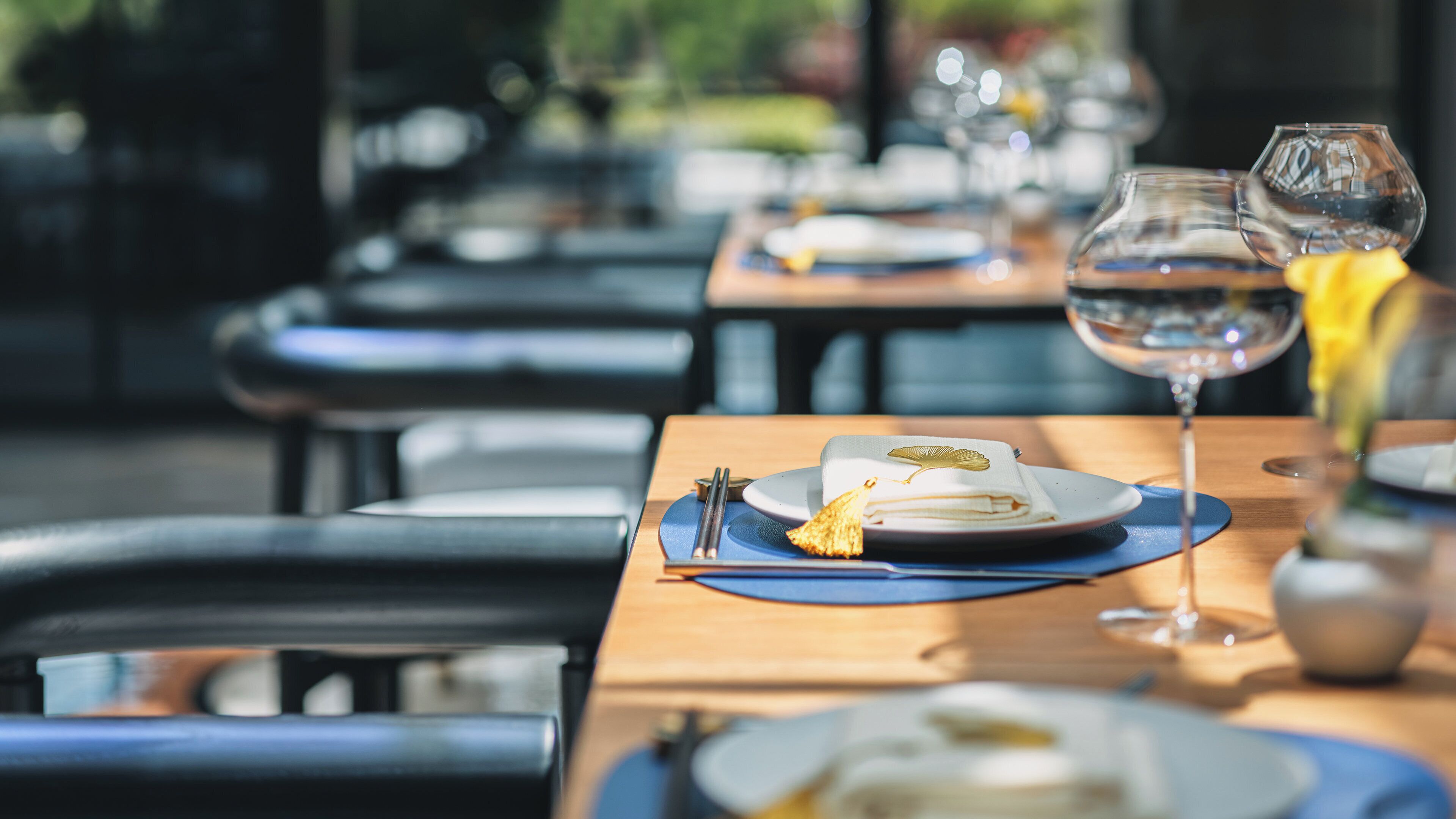 A dining table with a folded napkin, a plate, and a glass of water.
