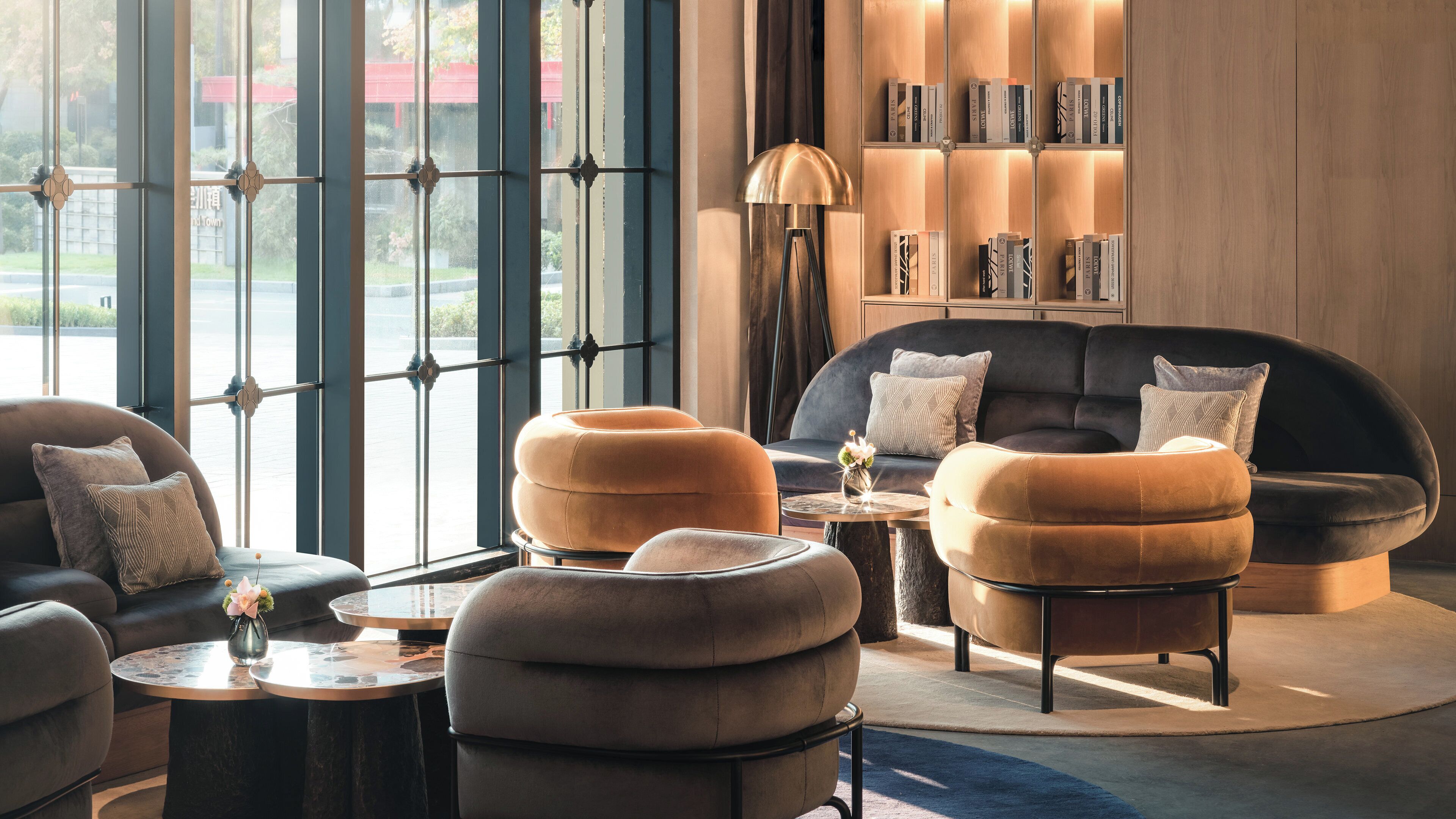 A modern living room with a sofa, ottomans, a coffee table, and a bookshelf.