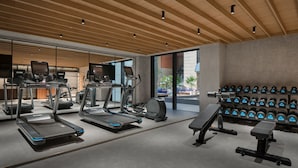 Un gimnasio moderno con cintas de correr, elípticas y una zona de pesas.