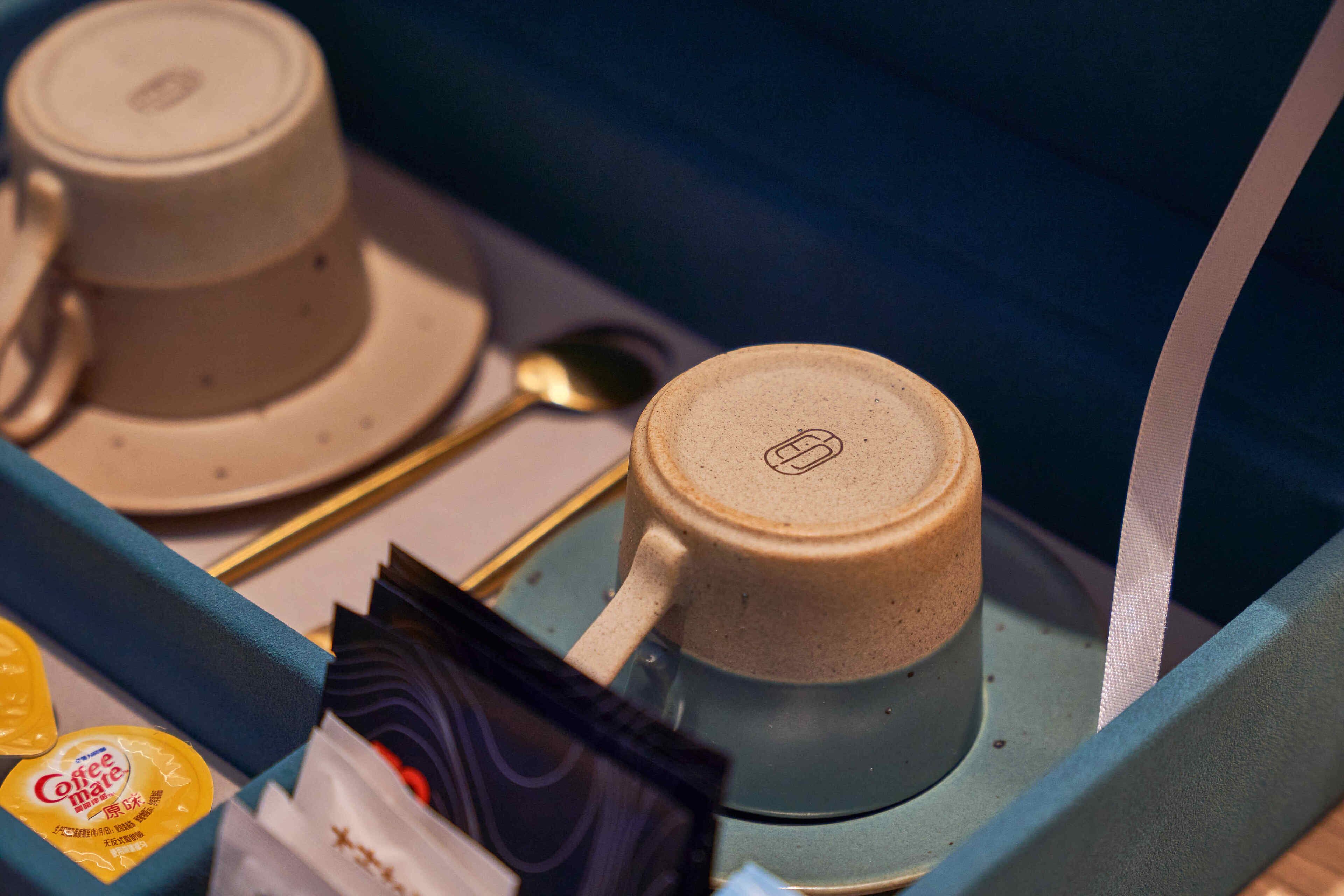 A tray with two coffee cups, a spoon, and a packet of coffee-mate.