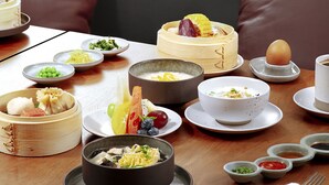 Une table à manger dressée avec différents plats, notamment un bol de soupe, des assiettes de nourriture et une tasse.