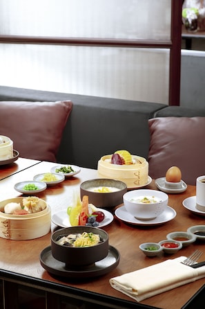 Une table à manger dressée avec différents plats, notamment un bol de soupe, des assiettes de nourriture et une tasse.