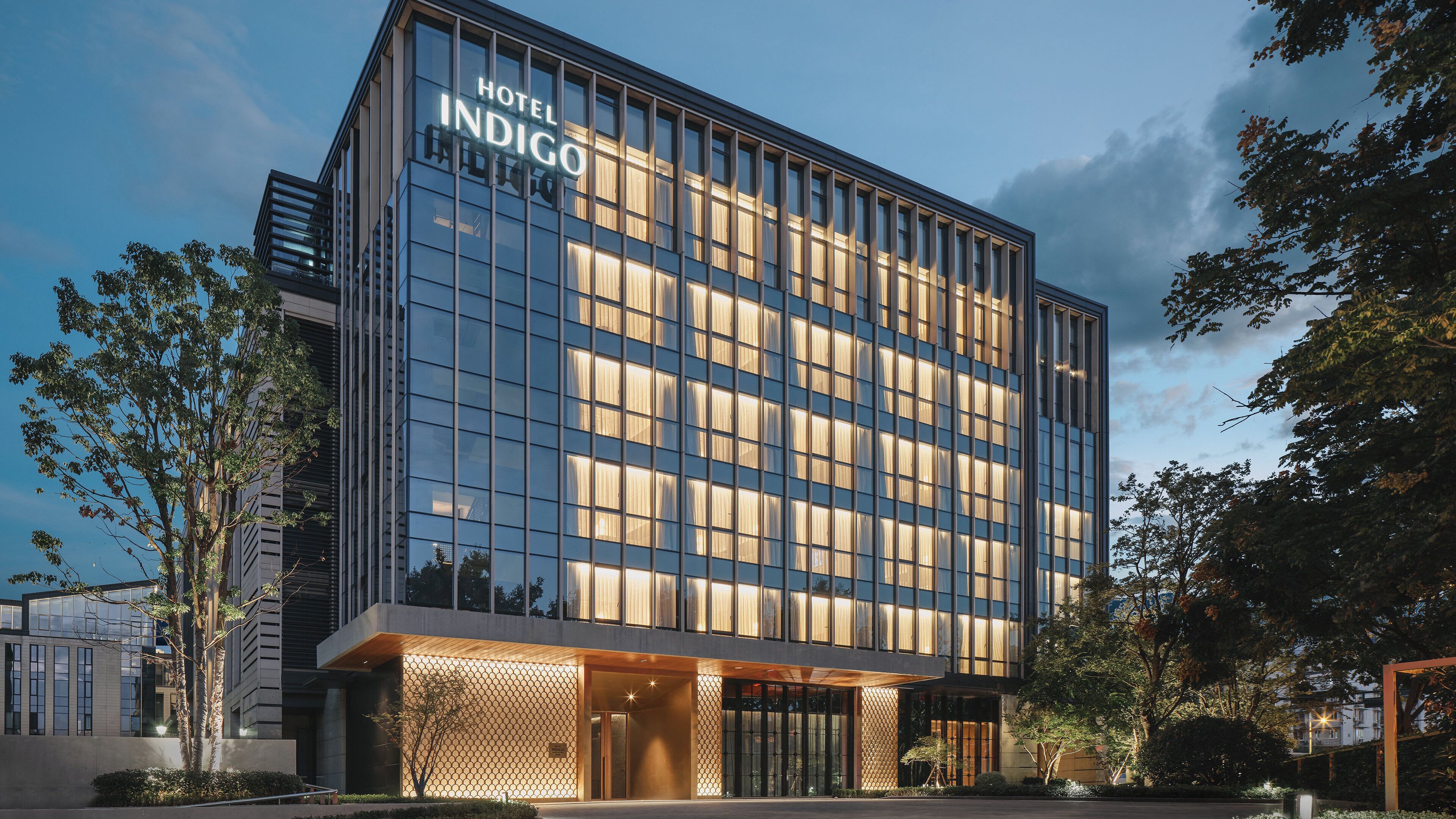 Un moderno edificio de hotel con fachada de vidrio y un letrero que dice 'Hotel Indigo'.