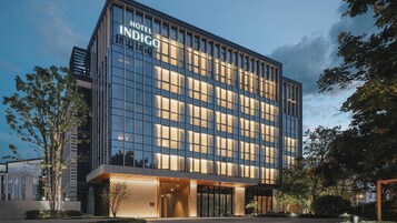 Un moderno edificio de hotel con fachada de vidrio y un letrero que dice 'Hotel Indigo'.