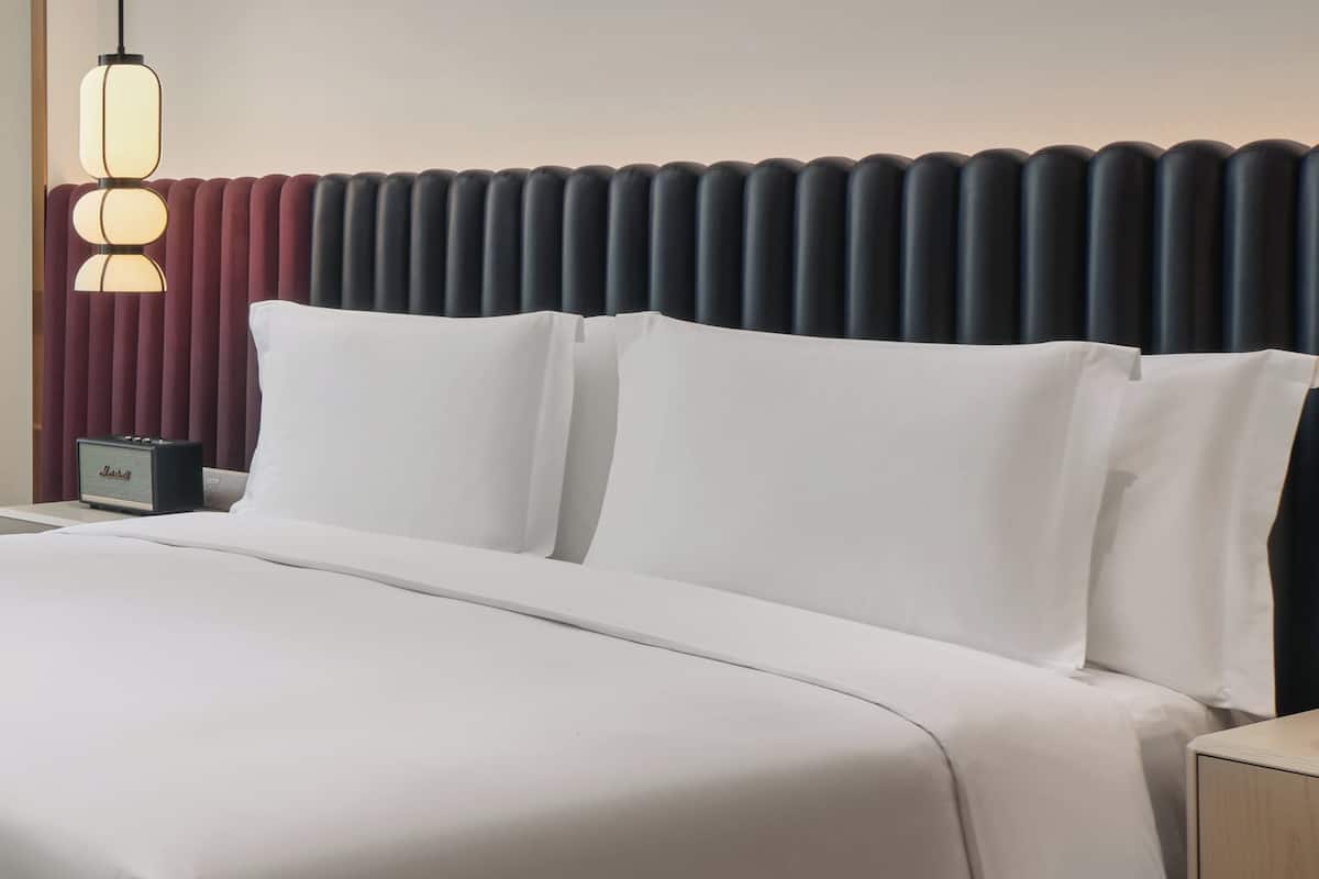 Ein Hotelzimmer mit einem Bett, einem Nachttisch, einer Lampe und einer Wand mit einem besonderen, strukturierten Design.