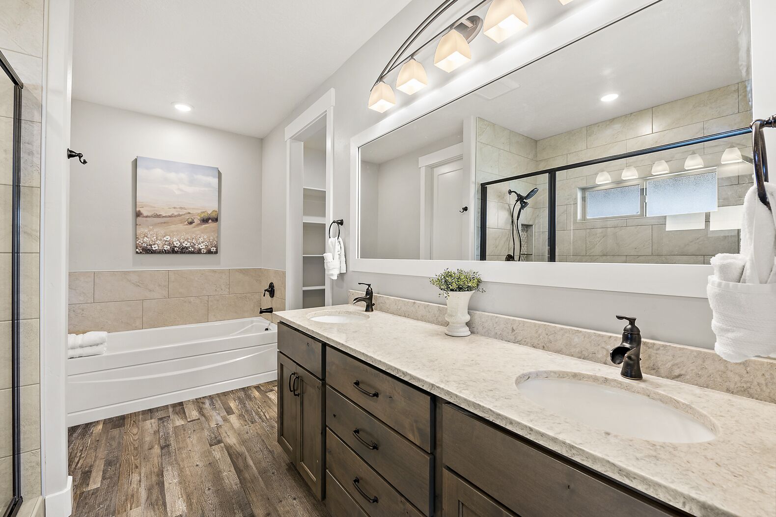 Un baño moderno con bañera, tocador doble, un espejo grande y cabina de ducha.
