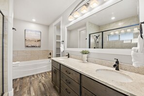 Une salle de bain moderne avec une baignoire, un meuble-lavabo à deux vasques, un grand miroir et un espace douche.