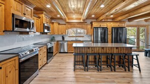 A spacious kitchen with wooden cabinets, stainless steel appliances, and a large island with bar stools.