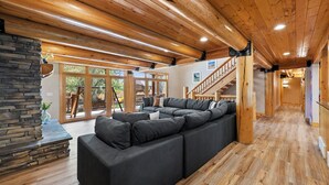 A spacious living area with a large sectional sofa, wooden flooring, and a stone fireplace.