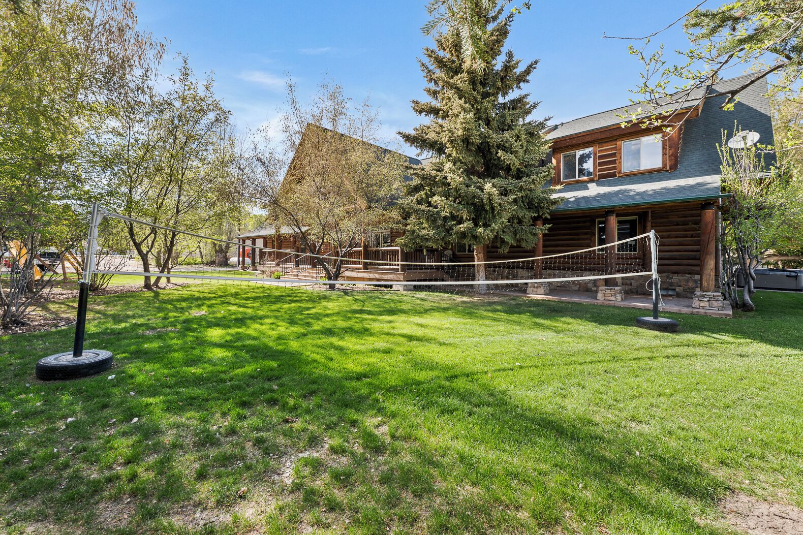 A log cabin with a well-maintained lawn and a volleyball net in the foreground.