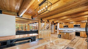 A spacious kitchen with wooden cabinets and a large island, a cozy seating area with a sofa, and a wooden dining table.